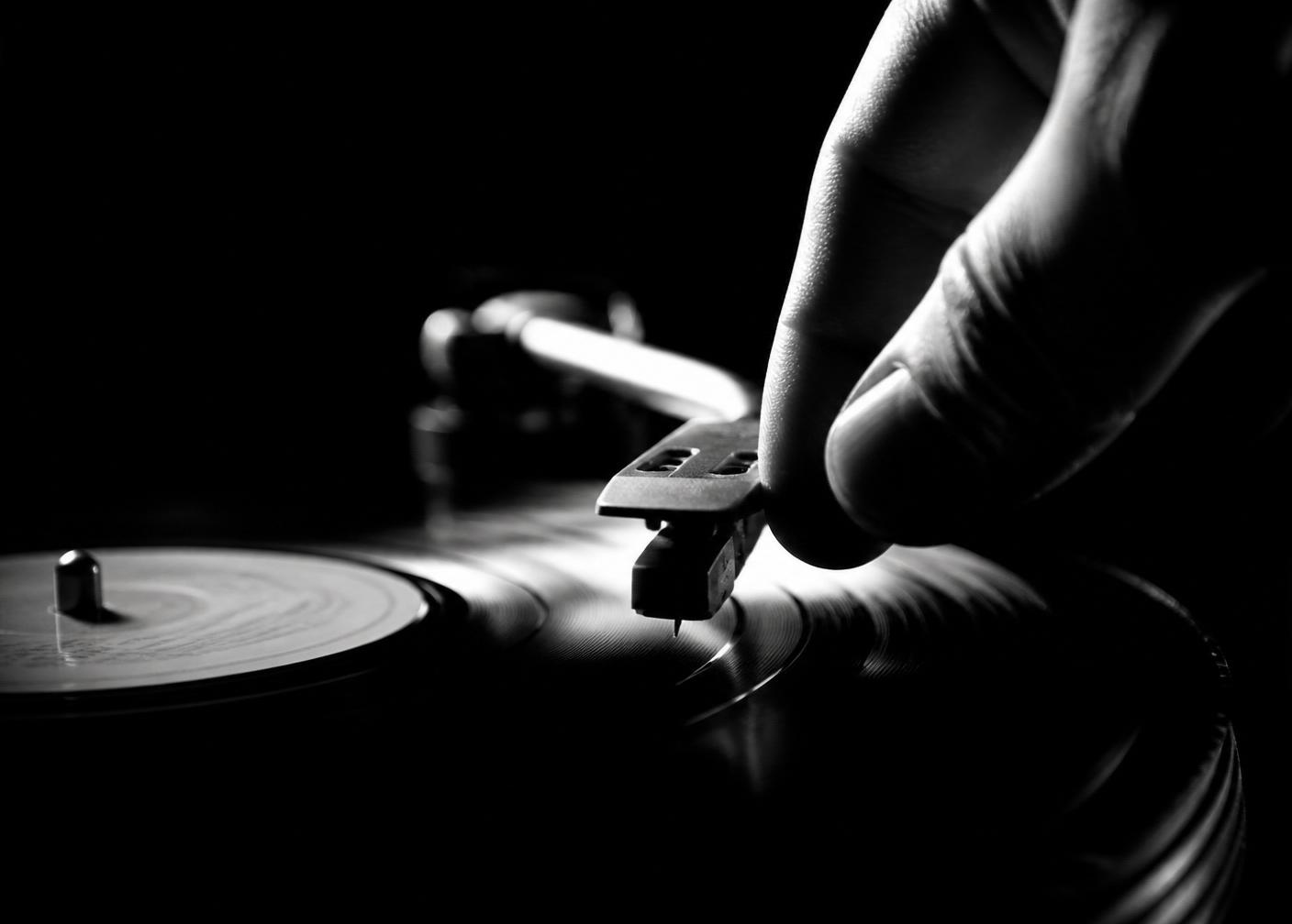 Hände legen eine Vinyl-Schallplatte auf